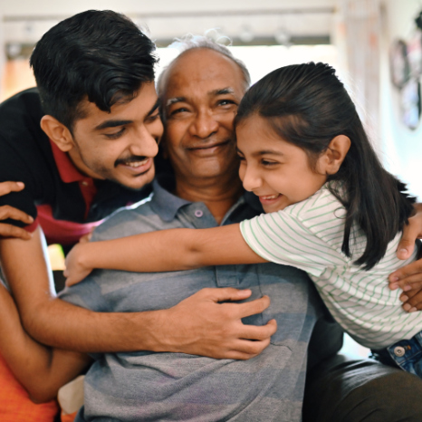 Elder grandson and younger granddaughter embracing their grandfather